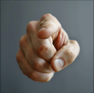 Close-up of a hand pointing directly at the viewer, index finger extended and knuckles visible.